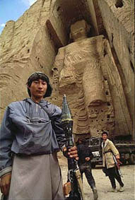 Un combattente Hazara sotto le colossali statue di Buddha di Bamiyan